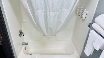 A bathroom with a bathtub, a shower curtain, and a towel rack with towels.