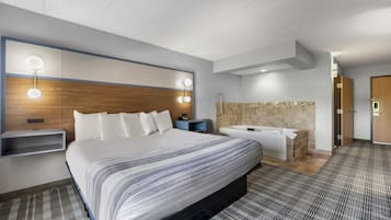 Ein Hotelzimmer mit einem großen Bett, Nachttischen, einem Schminktisch mit Spiegel und einem Duschbereich.