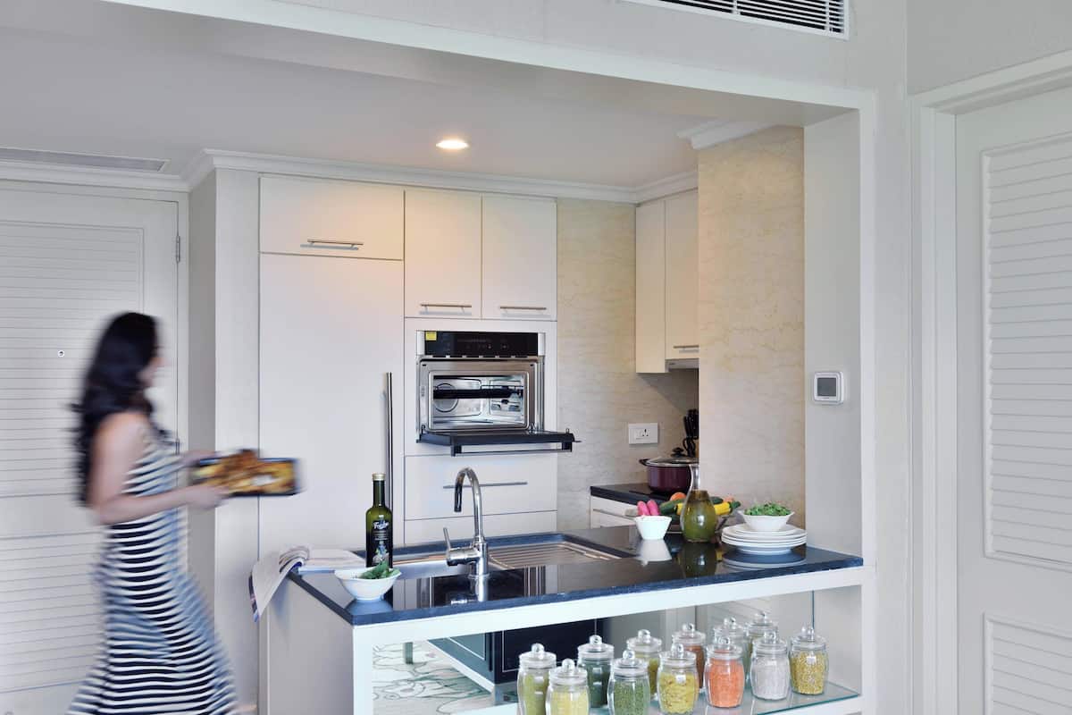 A modern kitchen with white cabinetry, a built-in oven, and a countertop with jars of condiments.