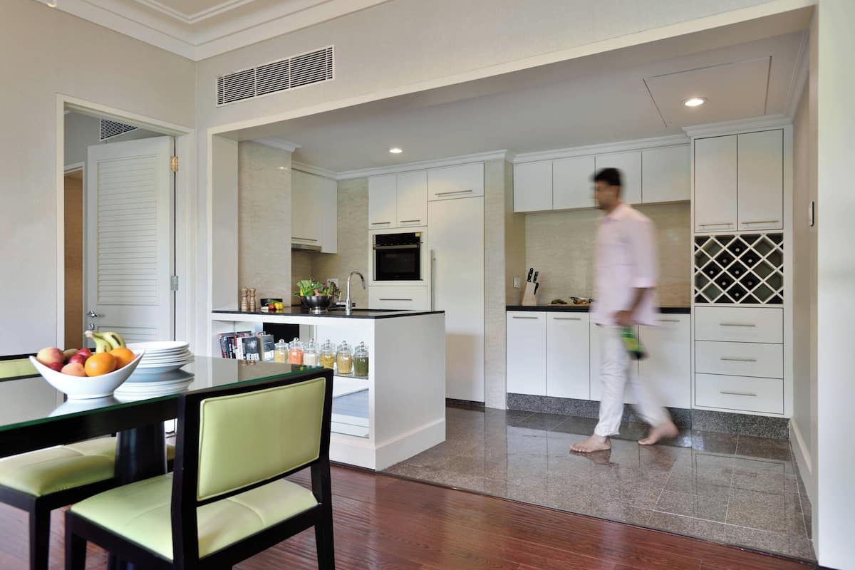 A modern kitchen with white cabinets, a central island with a sink, and a dining area with a table and chairs.