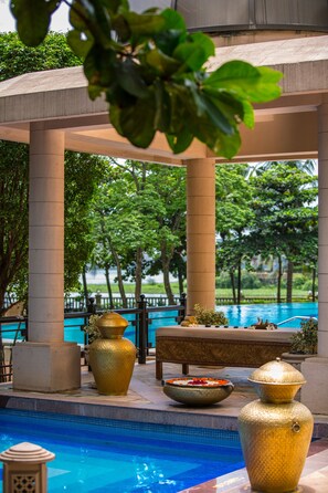A pool area with a pergola, large golden vases, and a bench. - Lakeside Chalet - Mumbai, Marriott Executive Apartments (Mumbai)
