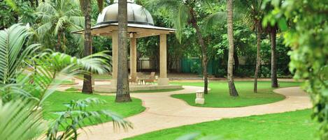 A gazebo with a dome roof surrounded by palm trees and a paved walkway.