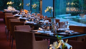 Um restaurante com mesas preparadas para refeições, com vasos de flores e copos de vinho.