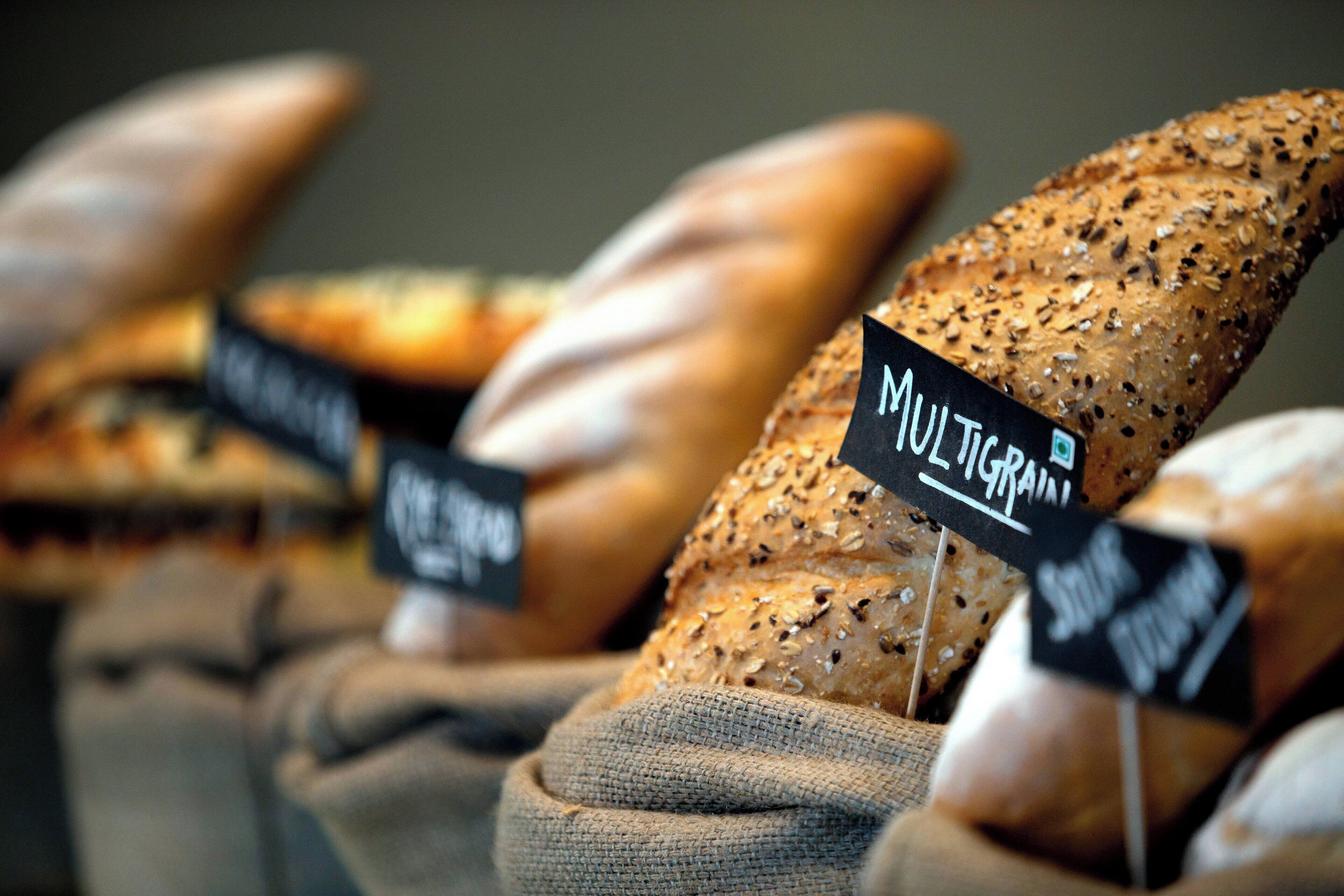 A variety of breads displayed in burlap sacks with labels indicating different types.