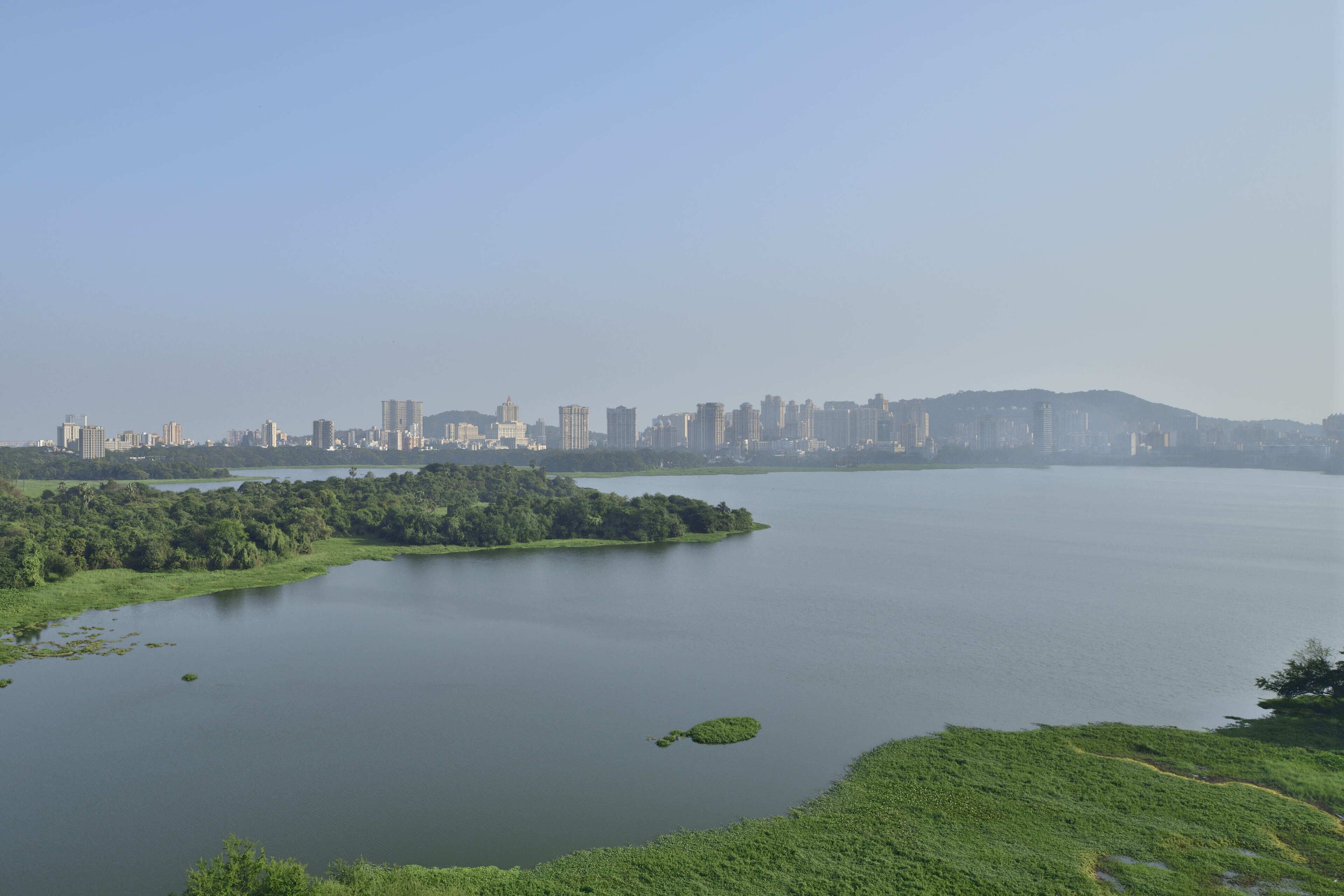 A city skyline across a body of water with a distant hill.