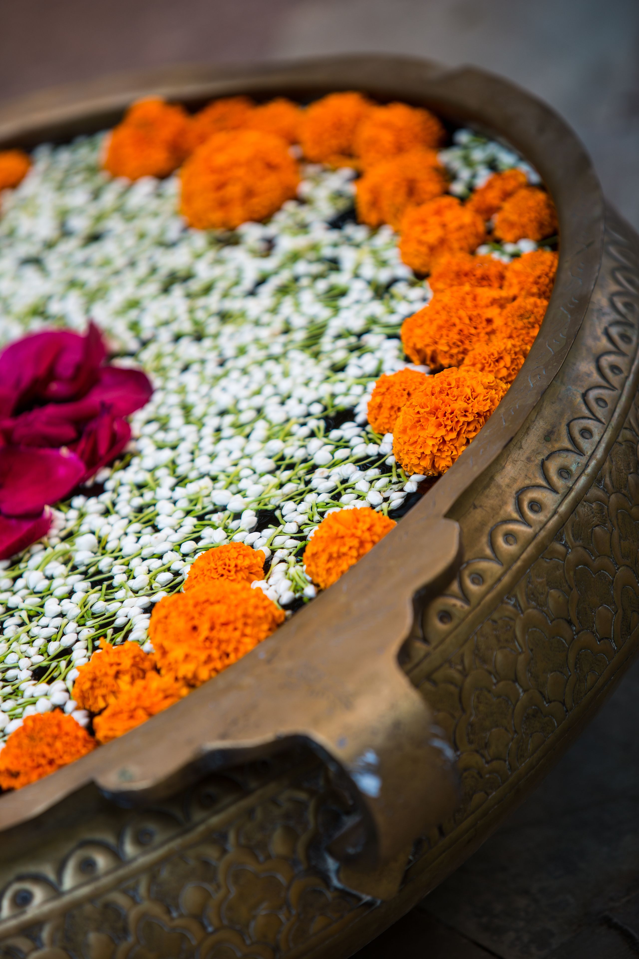 Un plateau décoratif orné de fleurs d’œillets d’Inde orange et de fleurs blanches, probablement utilisé à des fins cérémonielles.