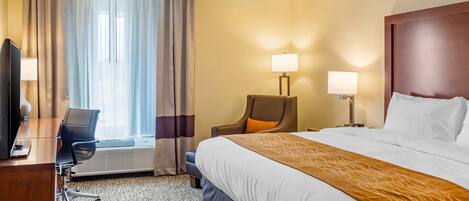 Een hotelkamer met een bed, bureau, stoel en twee lampen.