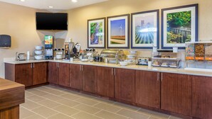 Una cucina d'hotel con un'area buffet, un televisore a schermo piatto e quadri appesi al muro.