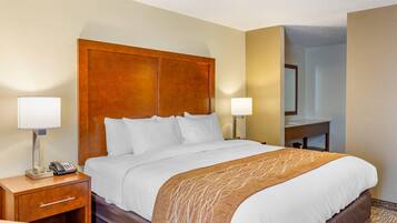 A hotel room with a large bed, bedside lamps, a desk with a phone, and a mirror.