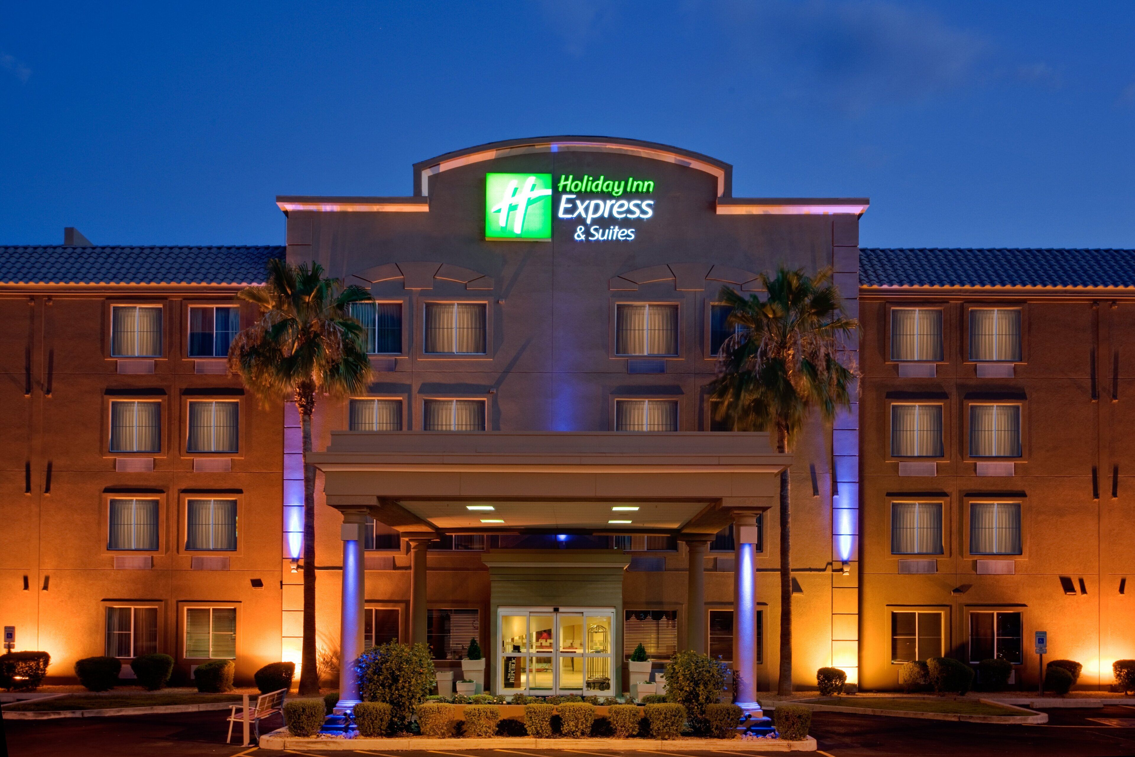 Edificio de Holiday Inn Express & Suites con un letrero llamativo, múltiples ventanas y una entrada bien iluminada.