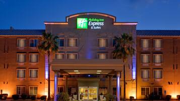 Edificio de Holiday Inn Express & Suites con un letrero llamativo, múltiples ventanas y una entrada bien iluminada.