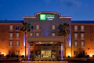 Edificio de Holiday Inn Express & Suites con un letrero llamativo, múltiples ventanas y una entrada bien iluminada.