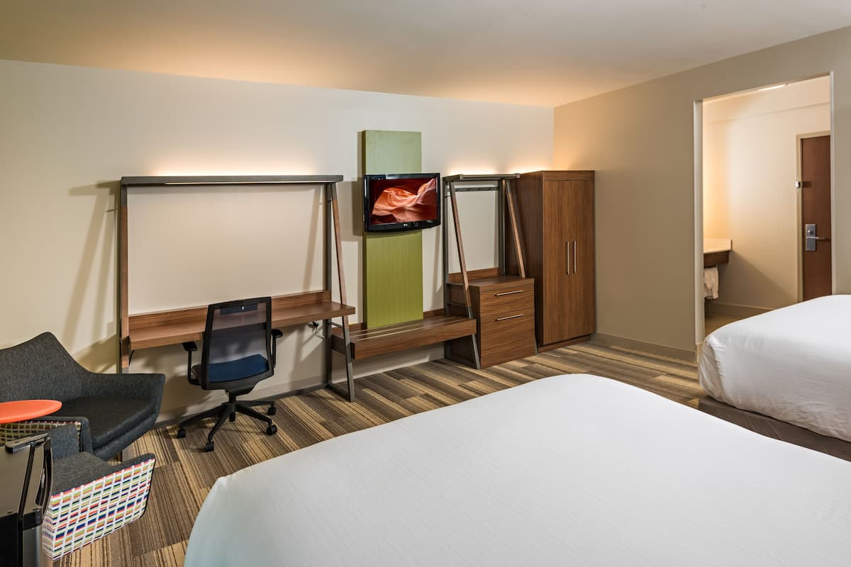 Ein Hotelzimmer mit einem Bett, einem Schreibtisch mit Stuhl, einem Fernseher und einem Kleiderschrank.