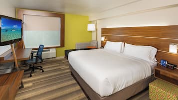 Une chambre d’hôtel comprenant un lit, un bureau avec un ordinateur, une chaise, une télévision et une table de chevet avec une lampe.