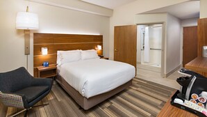 A hotel room with a large bed, a chair, a desk with a coffee maker, and a mirror. - Holiday Inn Express Hotel & Suites PEORIA NORTH - GLENDALE by IHG (Peoria)