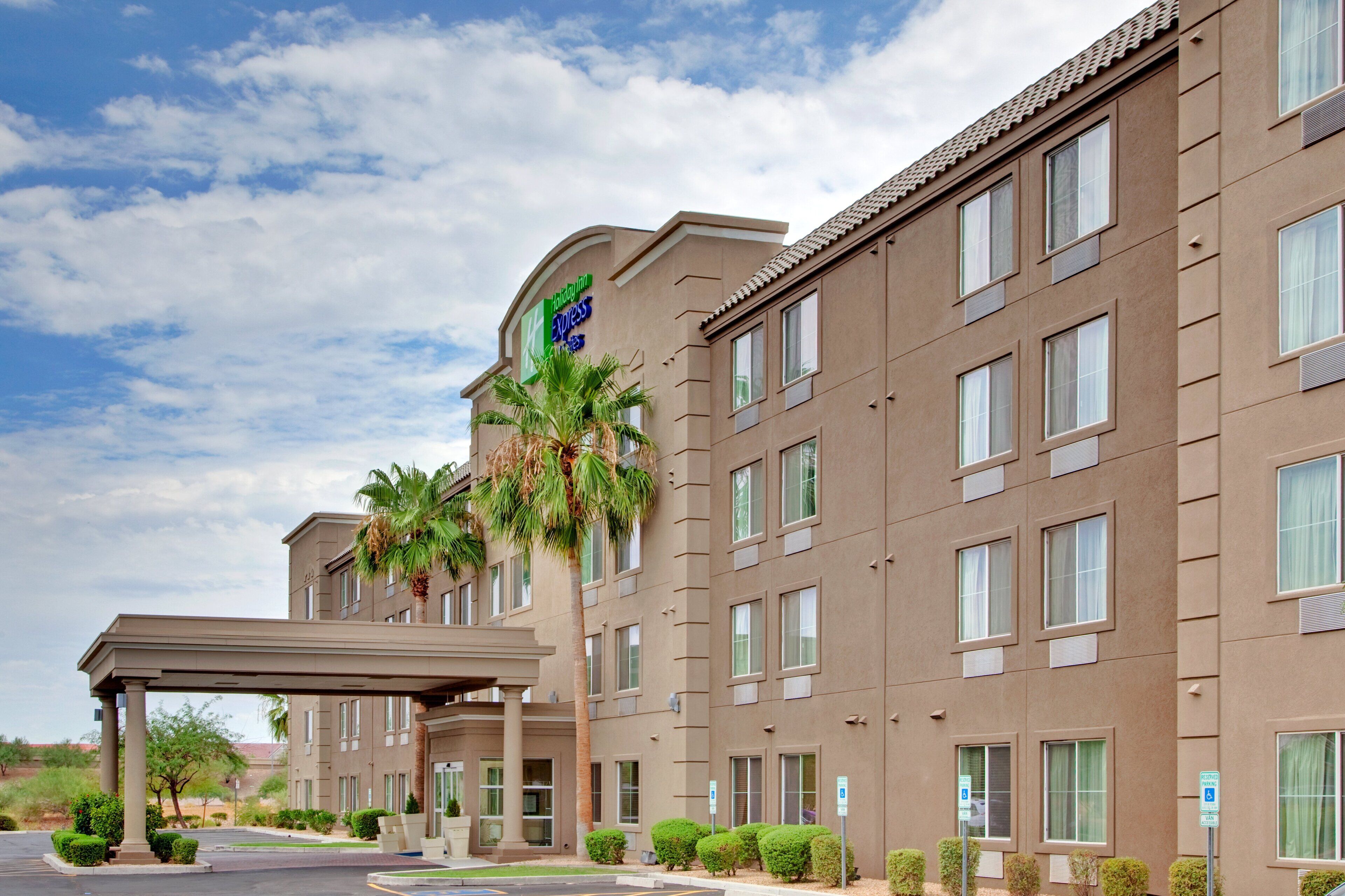 A Holiday Inn Express building with a covered entrance, multiple windows, and a palm tree.