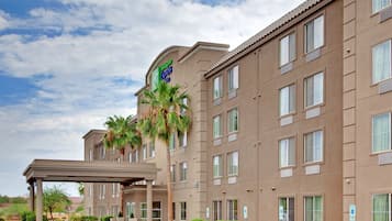 A Holiday Inn Express building with a covered entrance, multiple windows, and a palm tree.