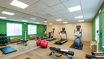 Une salle de sport équipée de divers appareils d’exercice, notamment des tapis de course, des vélos d’appartement et des poids libres.