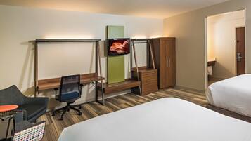 A hotel room with a bed, a desk with a chair, a television, and a wardrobe.