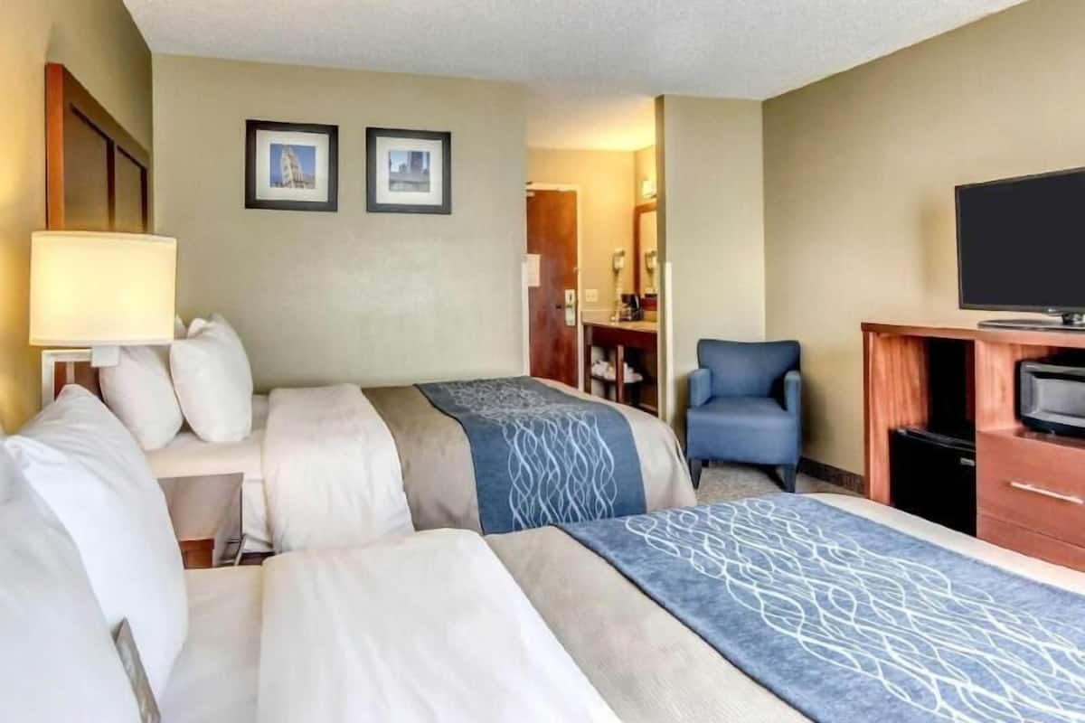 A hotel room with two beds, a TV, a desk, and a chair.