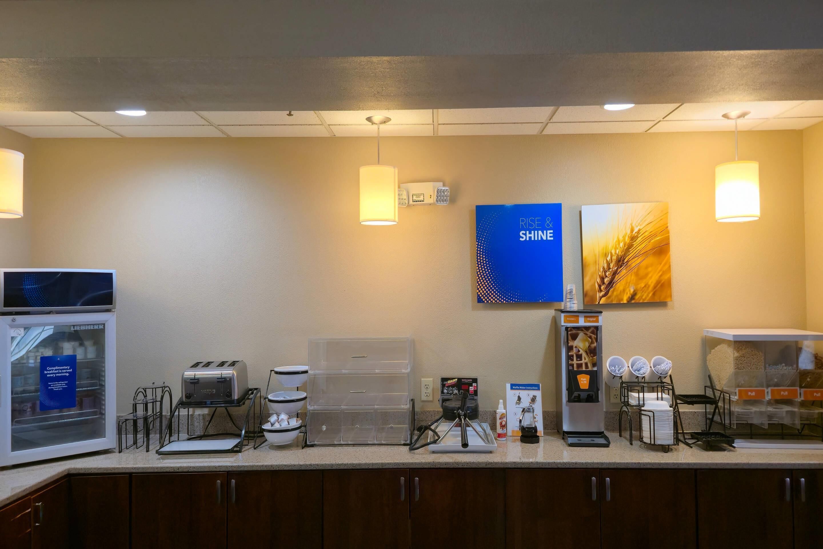 A hotel breakfast area with a coffee machine, toaster, and bread display.