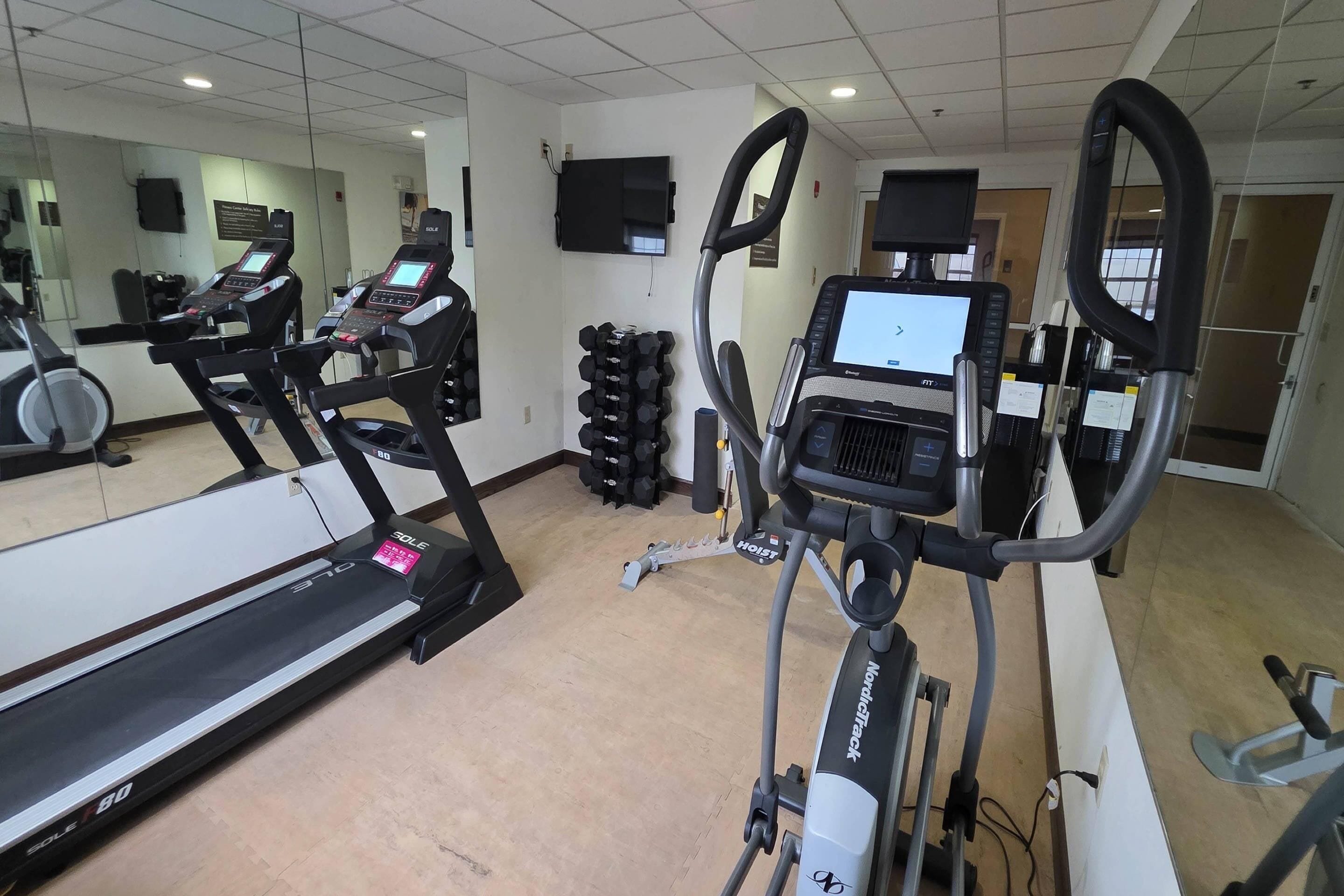 A gym with treadmills, elliptical machines, and weight stacks.
