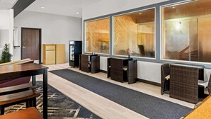 A modern hotel lobby with a reception desk, seating area, and large windows. - Americas Best Value Inn Tahquamenon Country (Newberry)