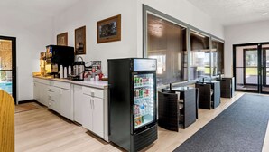 A modern kitchen with a refrigerator, coffee machine, and a large window. - Americas Best Value Inn Tahquamenon Country (Newberry)