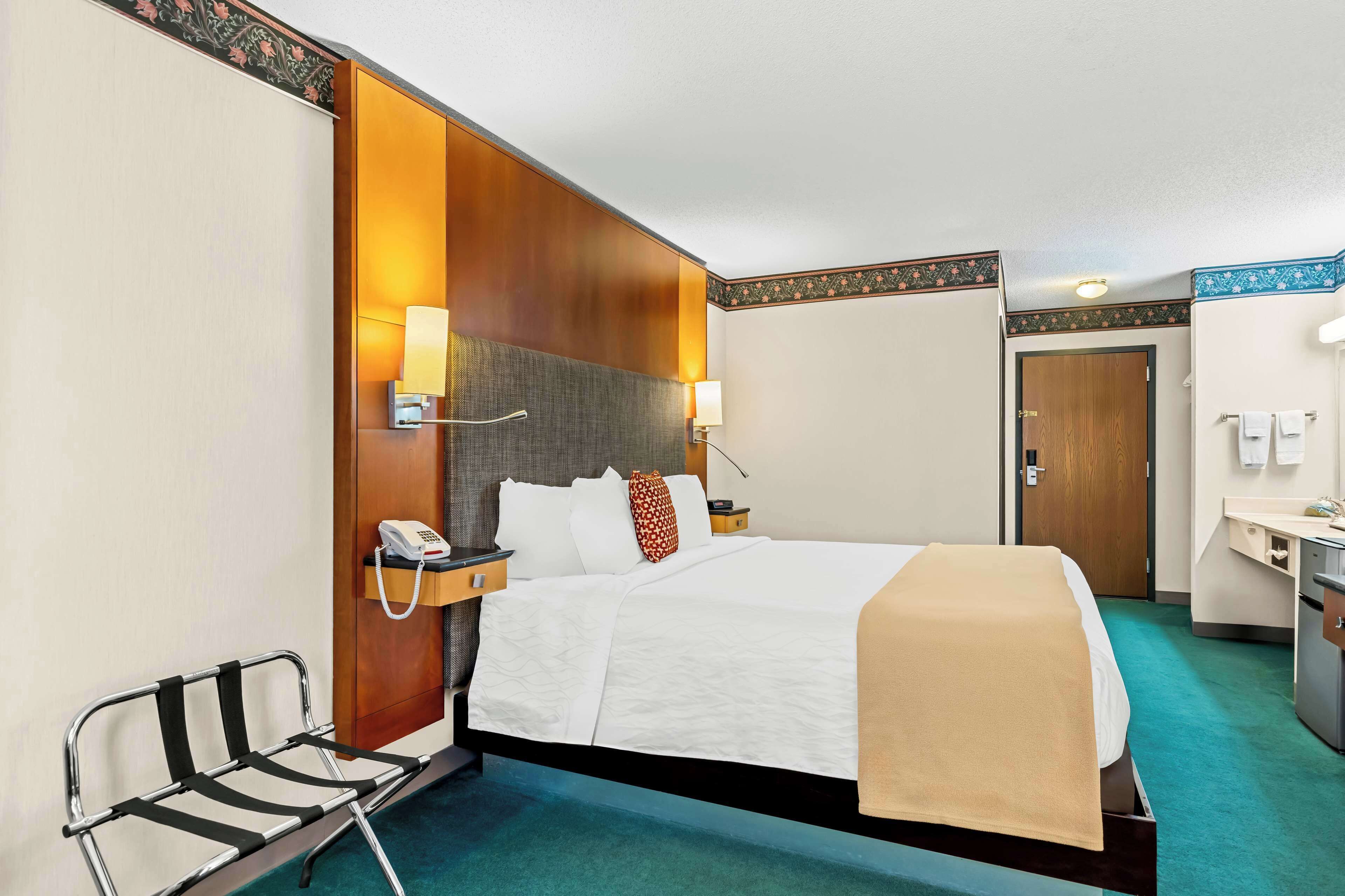 Une chambre d’hôtel équipée d’un lit, de lampes de chevet, d’un téléphone, d’un bureau et d’une chaise.