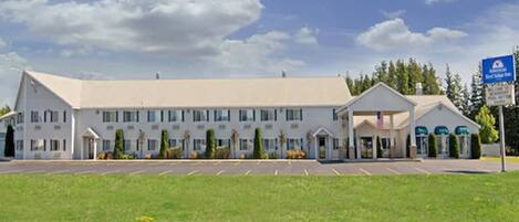 A large, single-story hotel with a central entrance and a parking lot in front.