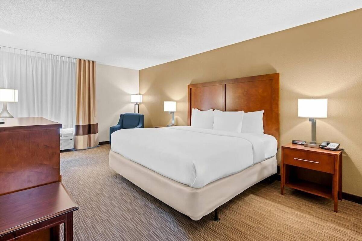 A hotel room with a large bed, bedside tables, a desk, and a chair.