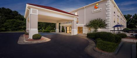 A Comfort Inn & Suites hotel with a covered entrance, a parking lot, and landscaped areas.