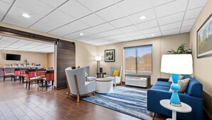 Hall d'hotel moderna con area ristorazione, posti a sedere e un'ampia finestra che offre una vista.