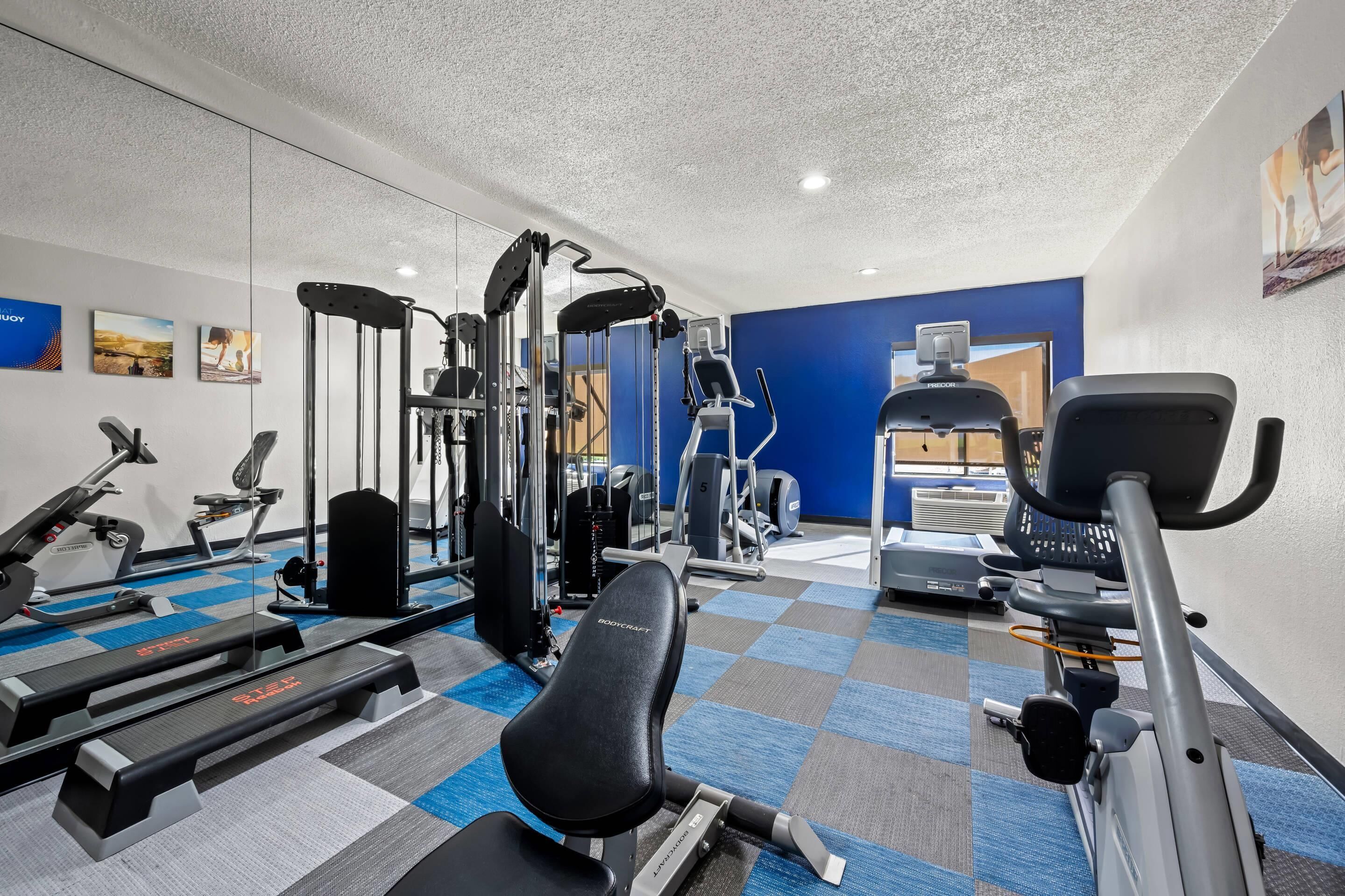 A gym with exercise equipment, a mirrored wall, and a blue accent wall.