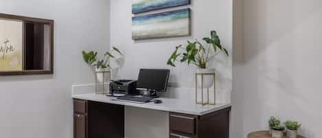 Un espacio de oficina moderno con un escritorio, computadora y dos plantas en macetas.