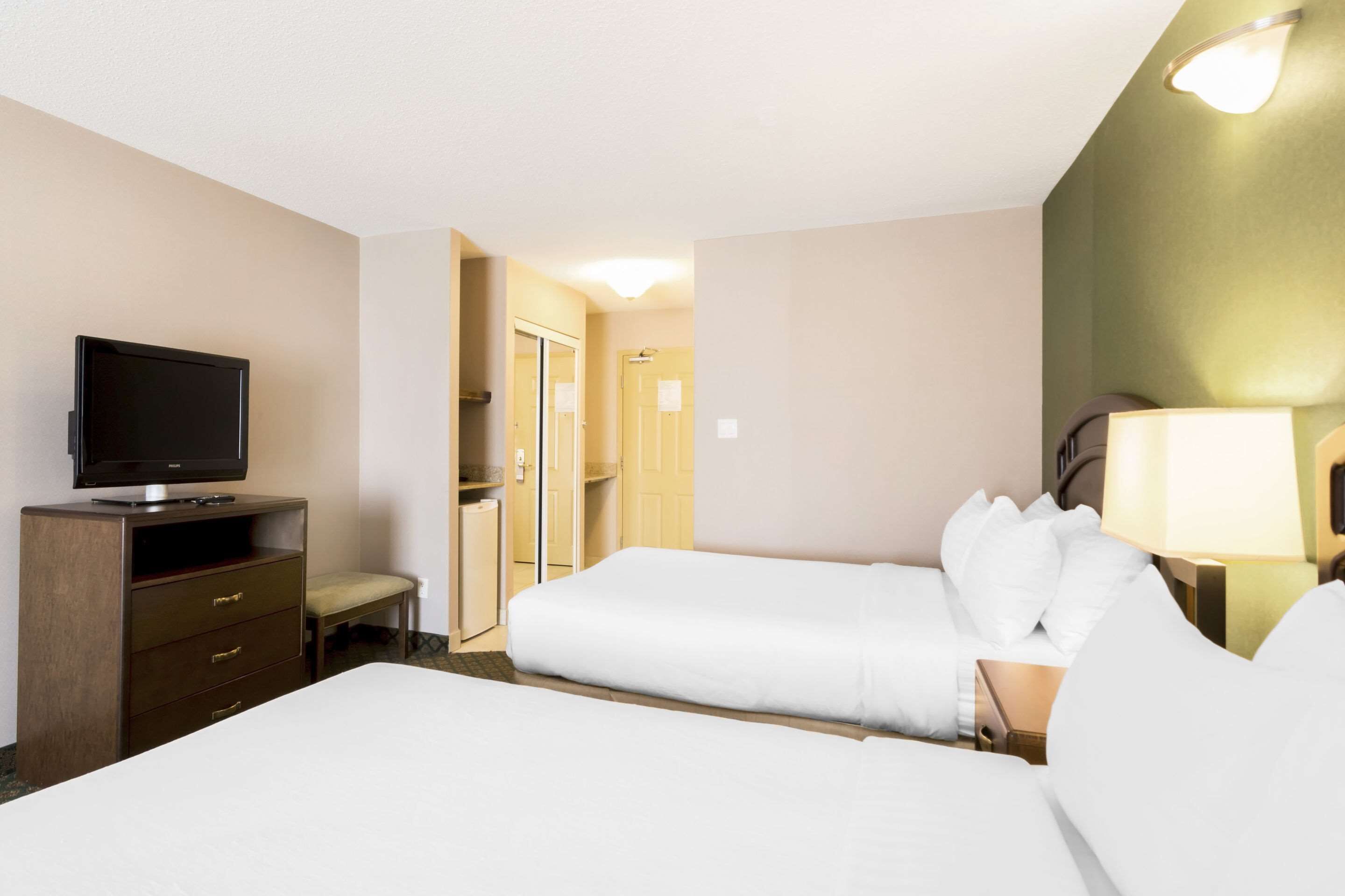 Habitación de hotel con dos camas, televisor, escritorio y una silla.