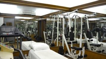 A gym with exercise equipment, a treadmill, and a mirrored wall.