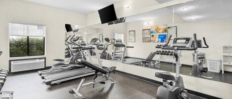 A gym with treadmills, stationary bikes, and a bench press.