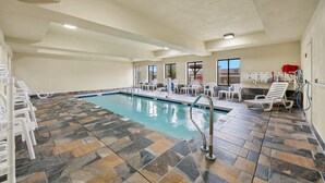 Una piscina interior amb paviment de rajola i gandules blanques.