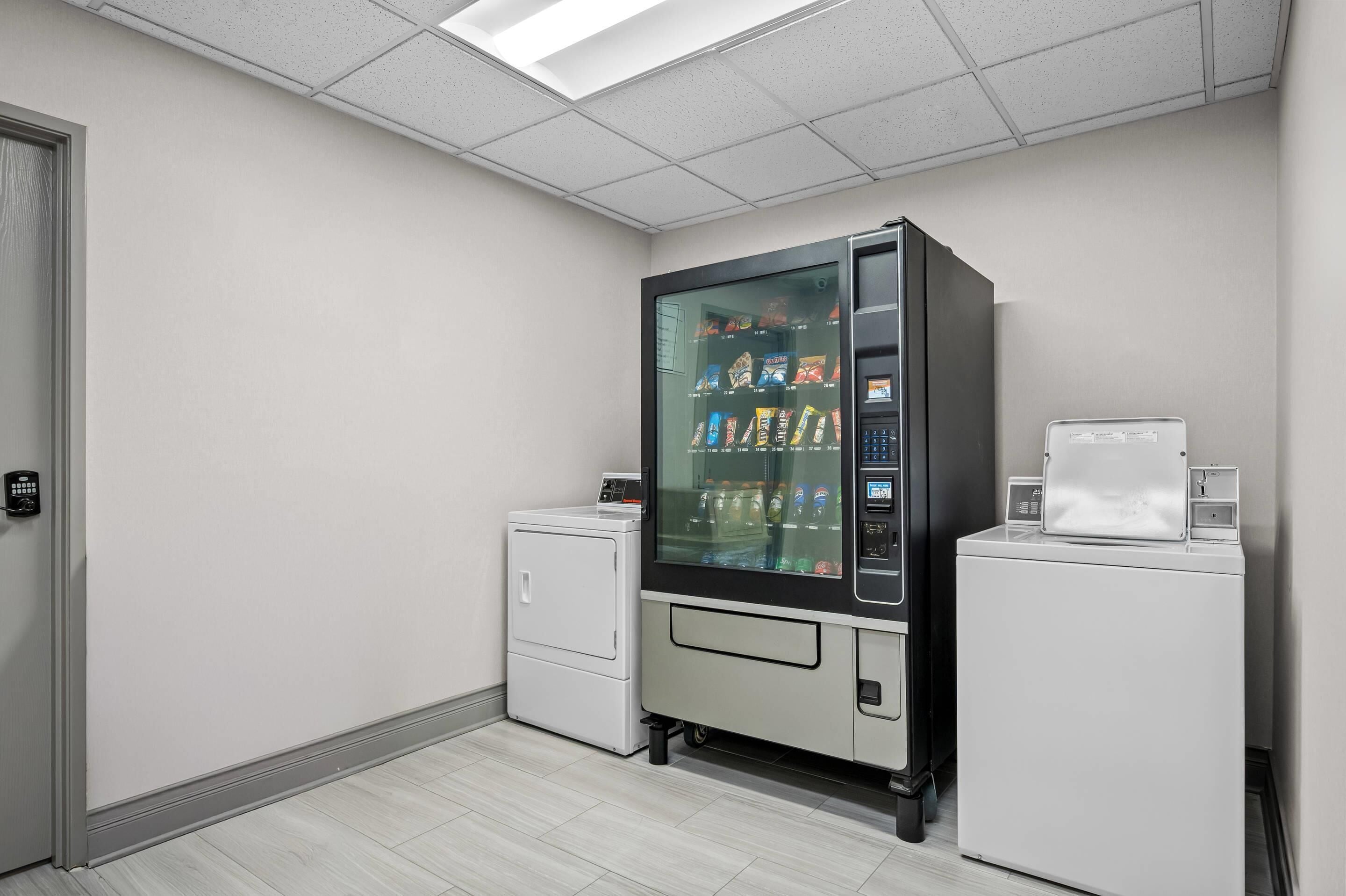 Une buanderie équipée d’un distributeur automatique, d’un lave-linge et d’un sèche-linge.