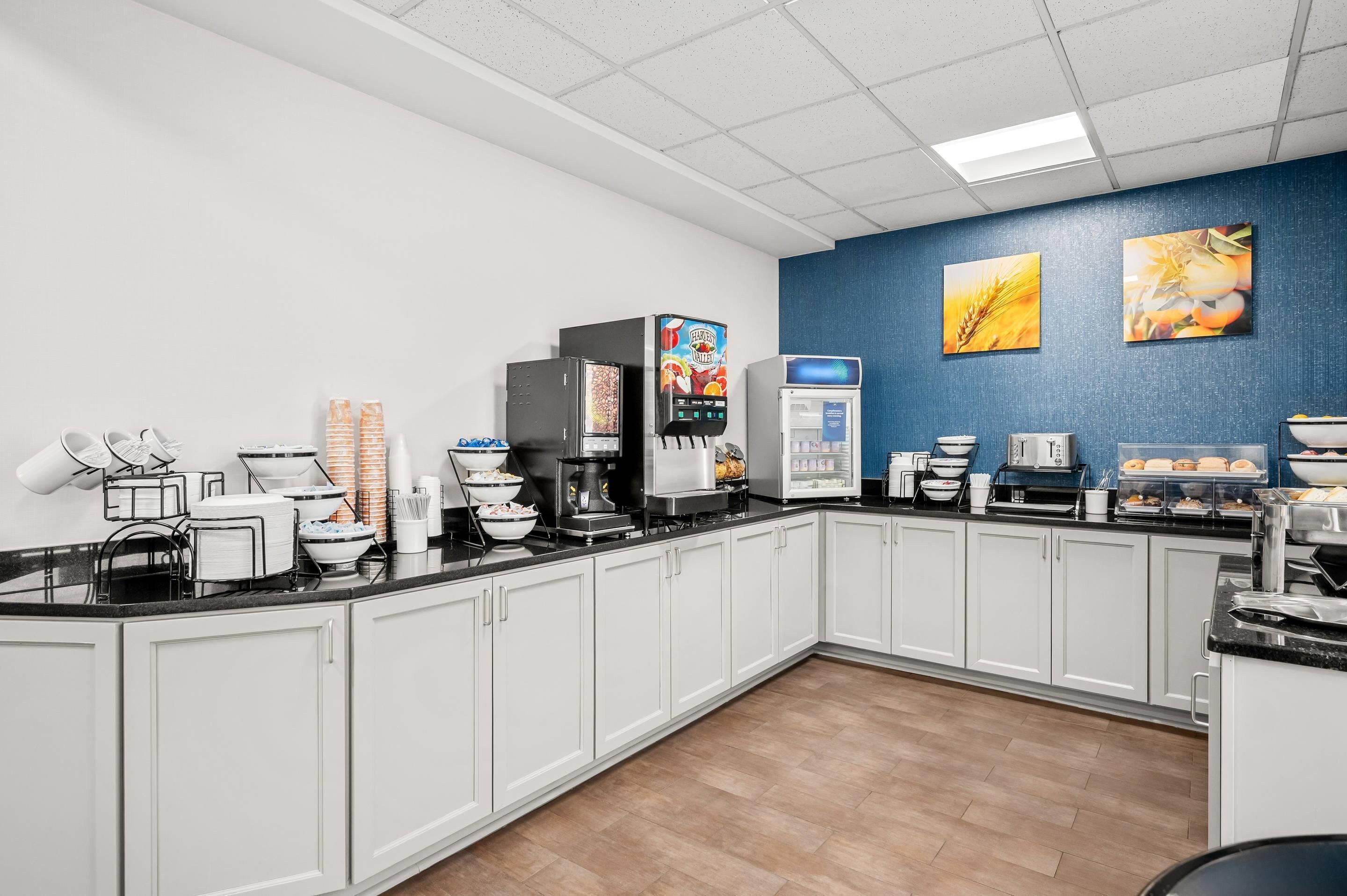 Eine moderne Küche mit weißen Schränken, einer Kaffeestation und einer Obstauslage.