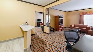A hotel room with a marble-tiled floor, a kitchenette, a sofa, a desk, and a television. - Quality Inn & Suites Lubbock South (Lubbock)