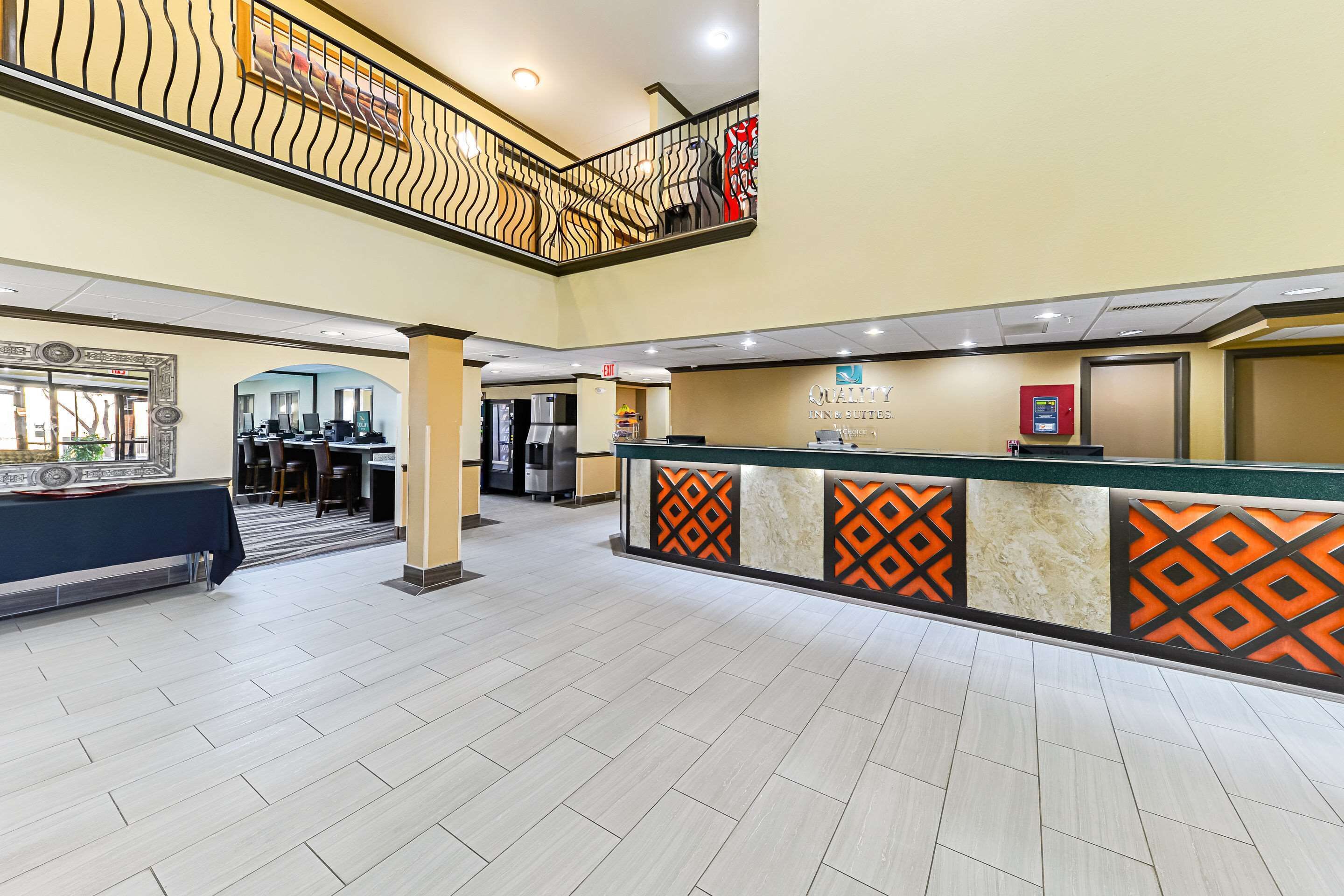 A hotel lobby with a reception desk, a staircase, and a view of the dining area.