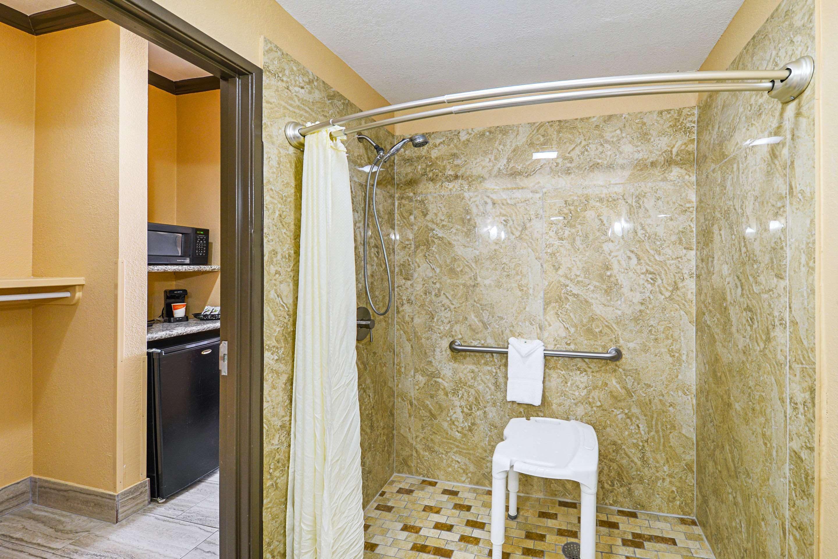 A shower with a glass door, a towel rack, and a small white stool.