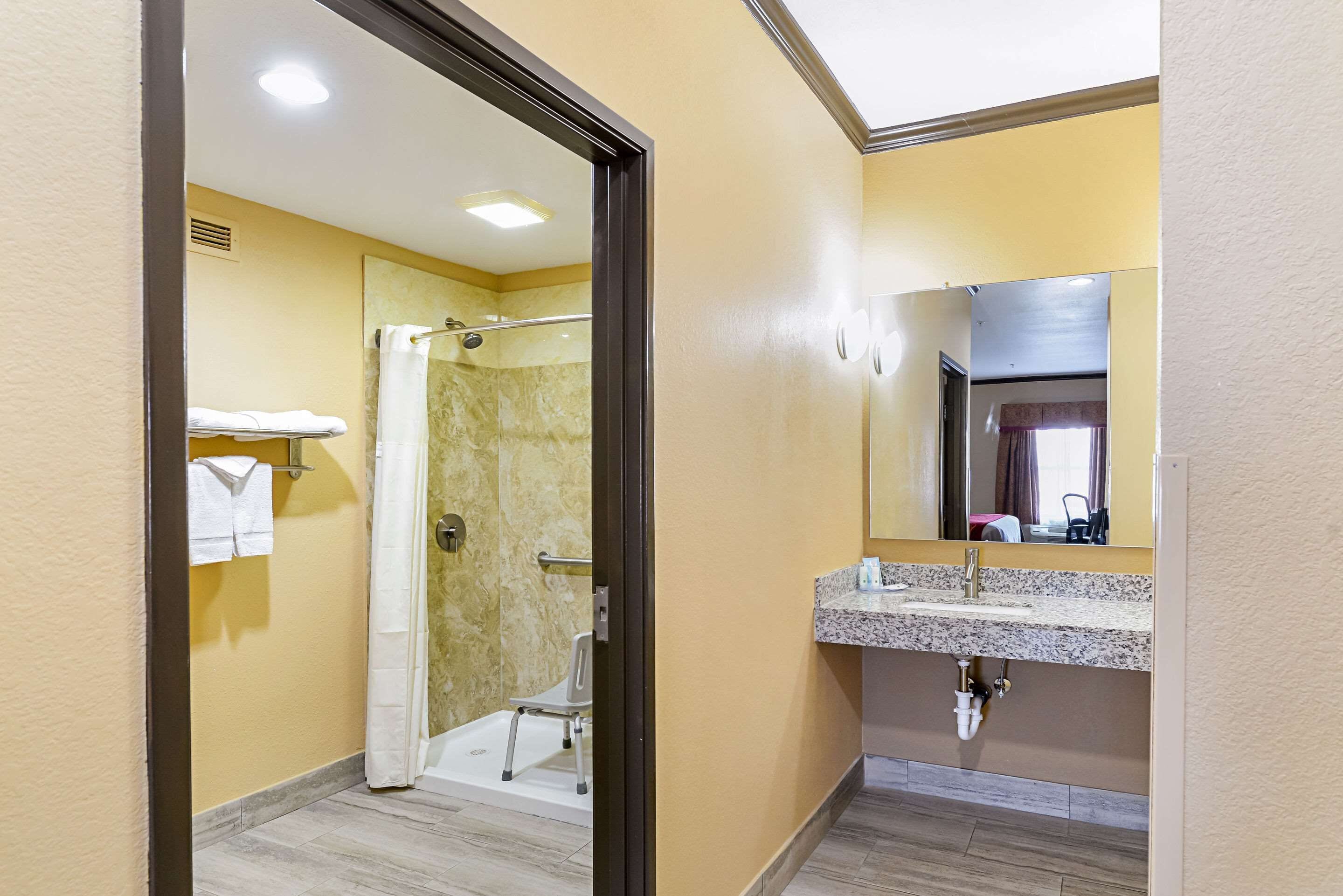 A bathroom with a shower, a sink, and a mirror.