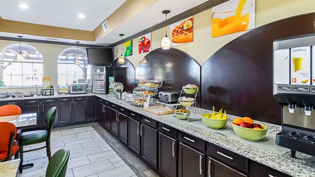 A modern kitchen with dark cabinets, a granite countertop, and various food items displayed. - Quality Inn & Suites Lubbock South (Lubbock)