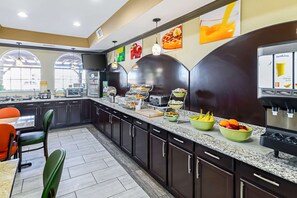 A modern kitchen with dark cabinets, a granite countertop, and various food items displayed. - Quality Inn & Suites Lubbock South (Lubbock)