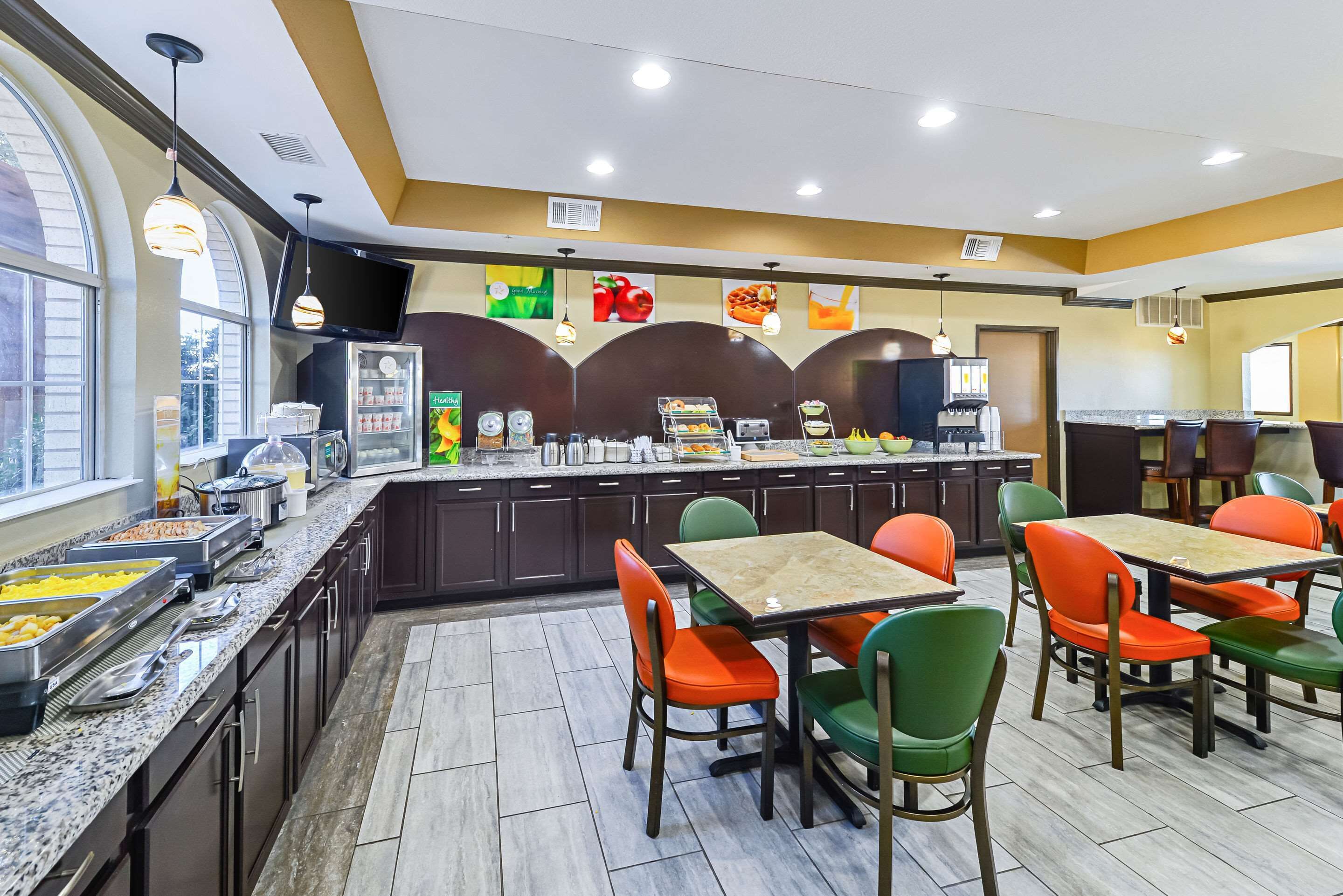 A breakfast area with a buffet, seating, and a TV screen.