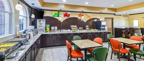 A breakfast area with a buffet, seating, and a TV screen.