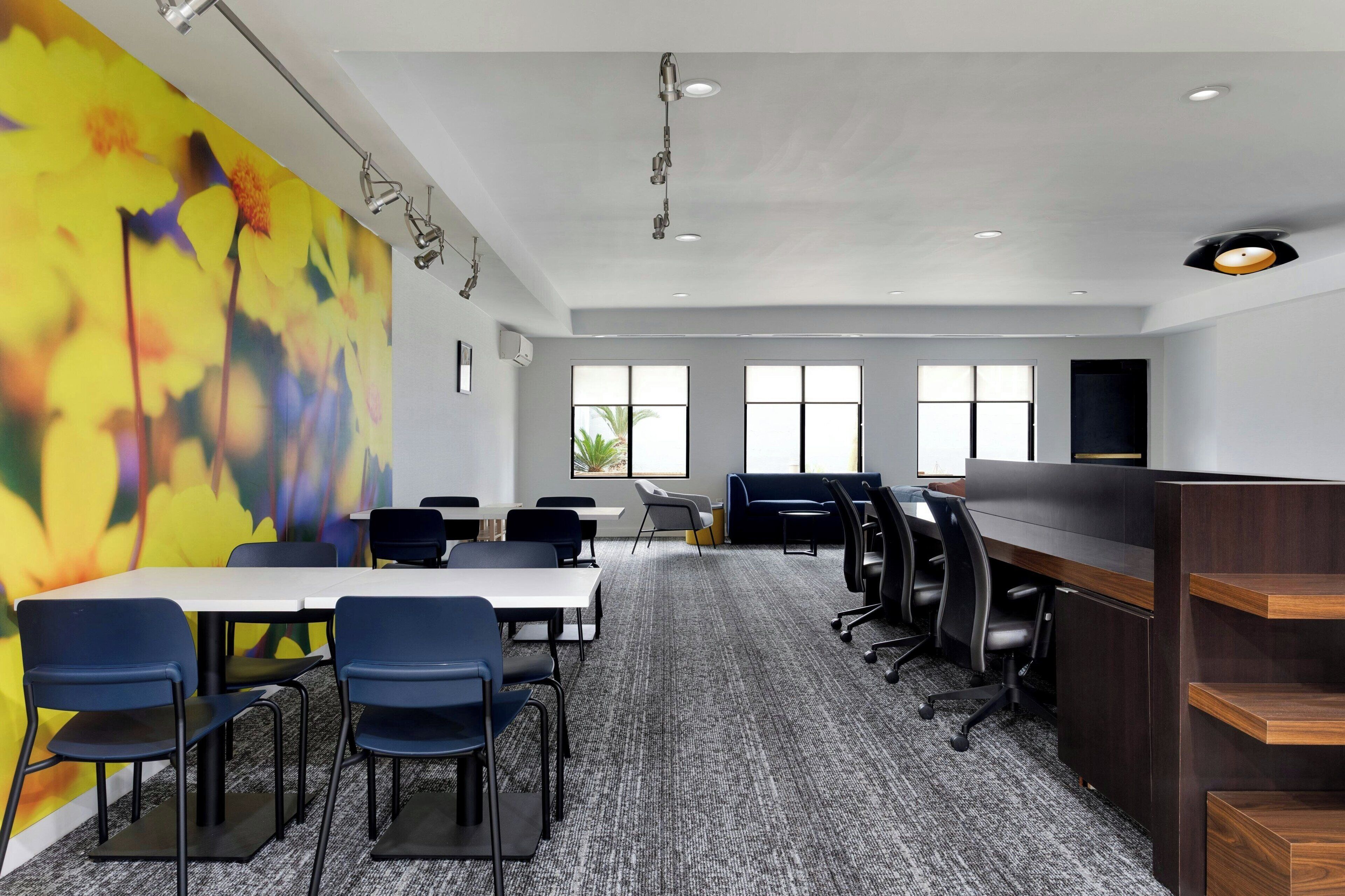 A conference room with a large table, chairs, a carpeted floor, and a colorful abstract wall.